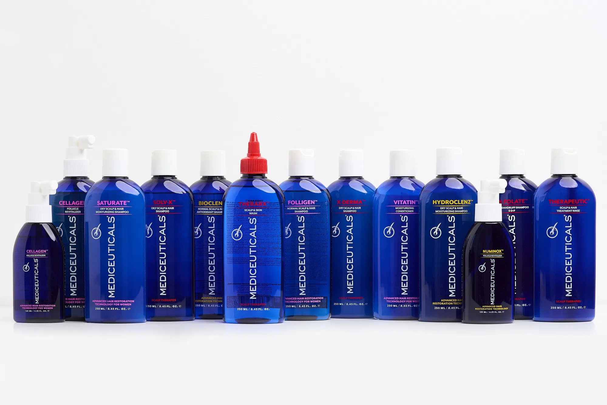 Een rij blauwe flessen van het merk Mediceuticals met shampoos, conditioners en behandelingen voor haar en hoofdhuid.